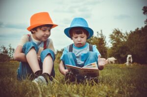 Deux garçons portant un chapeau regarde assis dans l'herbe